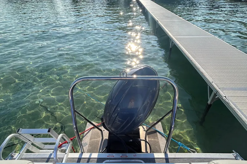 Slide: The Image of 2024 Bennington 22 SSR pontoon boat docked on clear water with sunlight reflections. - 7