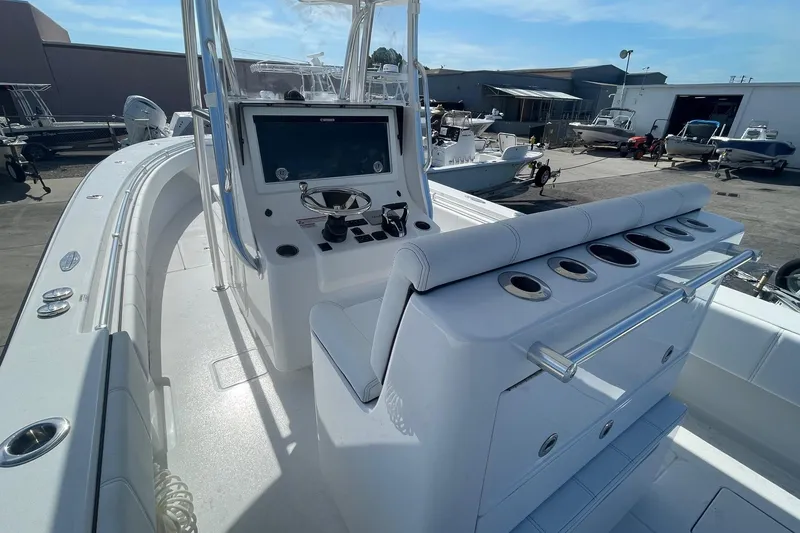 Slide: The Image of 2026 Contender 32 ST boat interior with helm, seating, and rod holders in a marina setting. - 5