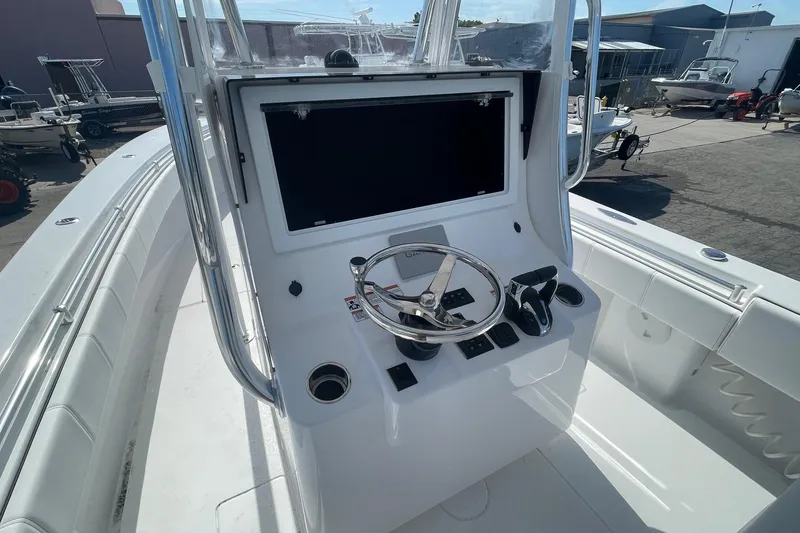 Slide: The Image of 2026 Contender 32 ST boat console with steering wheel and controls in a marina setting. - 7