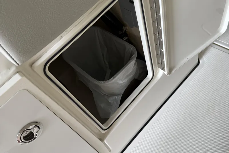 Slide: The Image of 2022 Pursuit S 328 Sport boat storage compartment with trash bin. - 11