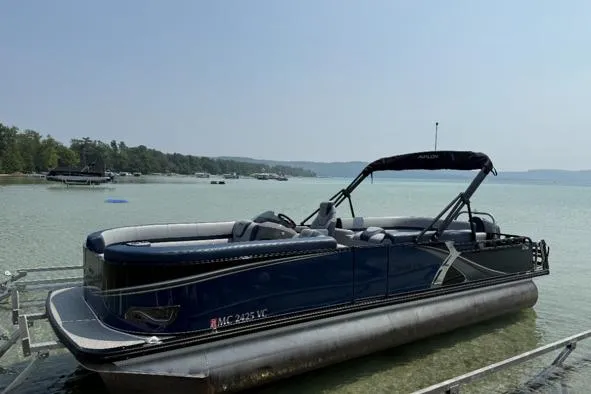 The Image of 2025 Avalon 25 LSZ Elite pontoon boat on calm lake waters. - 1
