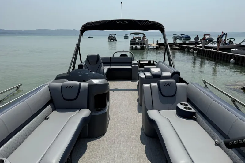 Slide: The Image of 2025 Avalon 25 LSZ Elite pontoon boat with luxurious seating, docked by a serene lake. - 3