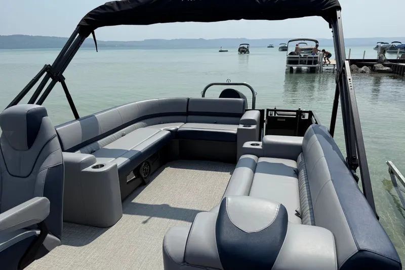 Slide: The Image of 2025 Avalon 25 LSZ Elite pontoon boat with spacious seating on a serene lake. - 4