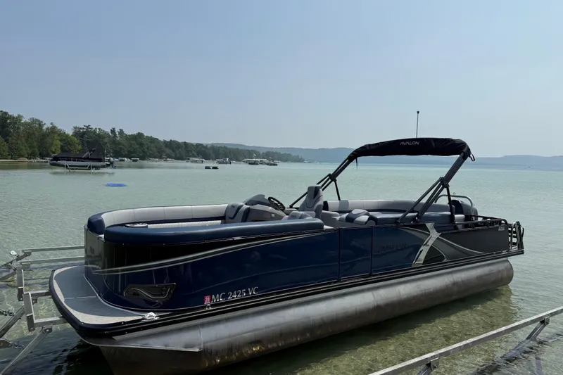 Slide: The Image of 2025 Avalon 25 LSZ Elite pontoon boat docked on a serene lake. - 7