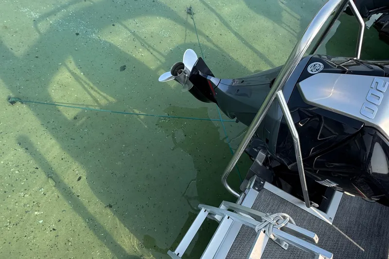 Slide: The Image of 2024 Bennington 25 SSR boat engine in clear water, showcasing propeller and ladder. - 3