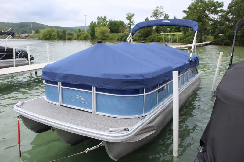 Slide: The Image of 2024 Bennington 25 SSR pontoon boat with blue cover docked on a lake. - 4