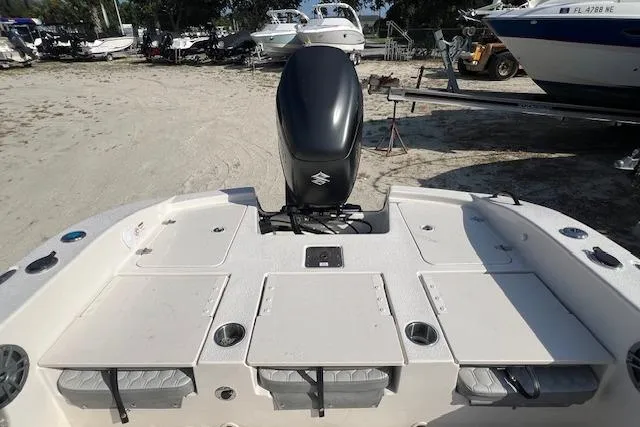 Slide: The Image of 2026 Carolina Skiff 24 Ultra Elite boat with Suzuki outboard motor, docked on sandy shore. - 2