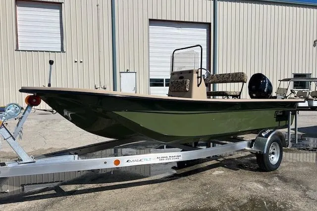 The Image of 2026 Carolina Skiff E18 JVX CC boat on trailer, parked outside a warehouse. - 0