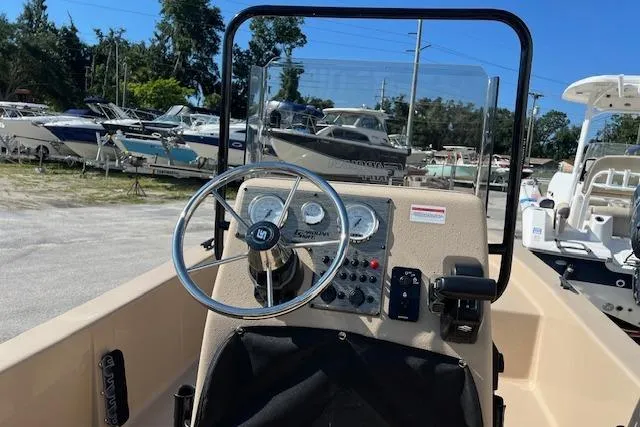 Slide: The Image of 2026 Carolina Skiff E18 JVX CC boat console with steering wheel and gauges, docked among other boats. - 7