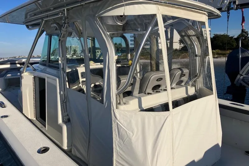 Slide: The Image of 2012 Yellowfin 42 Offshore boat with enclosed helm, docked near a scenic shoreline. - 17