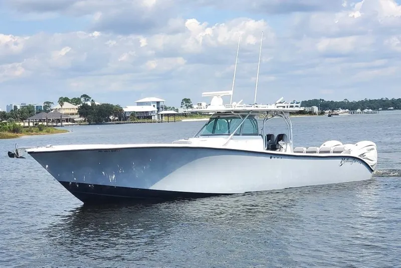 Slide: The Image of 2012 Yellowfin 42 Offshore boat cruising on a calm waterway under a cloudy sky. - 2