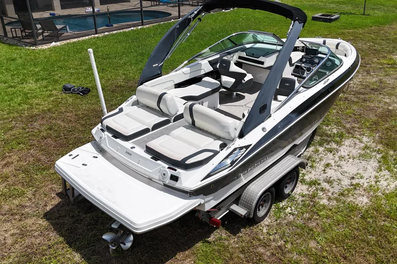 Slide: The Image of 2018 Regal 2300 Bowrider boat on trailer, parked on grass near a pool. - 3
