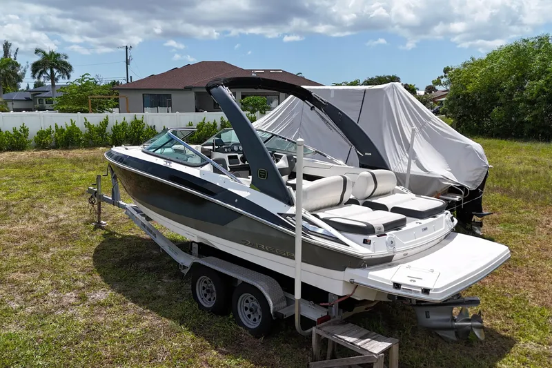 Slide: The Image of 2018 Regal 2300 Bowrider boat on trailer in grassy yard, under partly cloudy sky. - 4