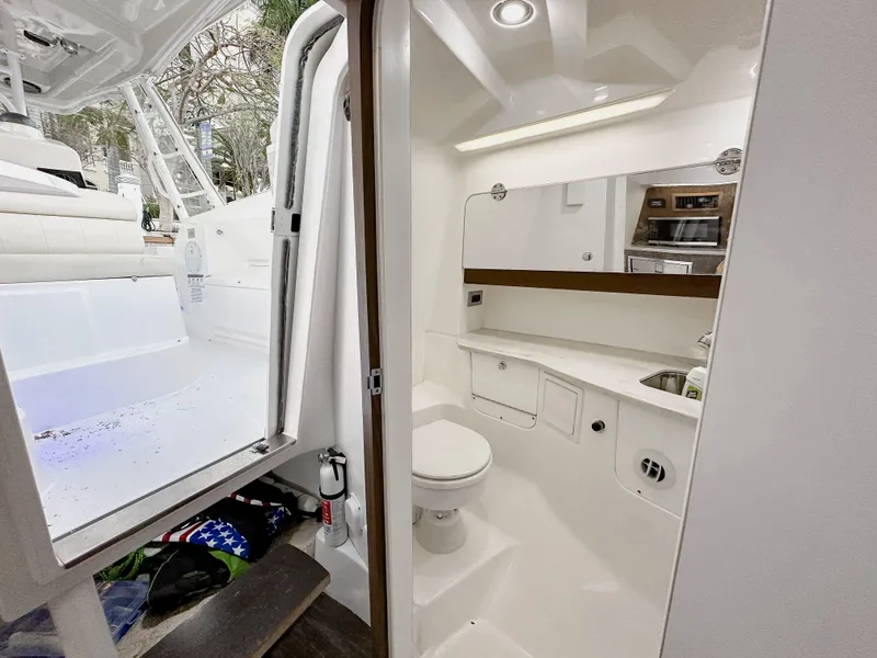 Slide: The Image of Interior of 2017 Everglades 360 LXC boat, featuring a compact bathroom with modern amenities. - 22