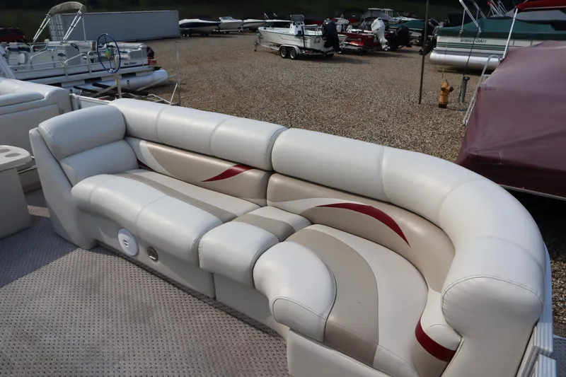 Slide: The Image of 2005 Crest 25 Caribbean boat interior with white and beige seating, parked among other boats. - 11