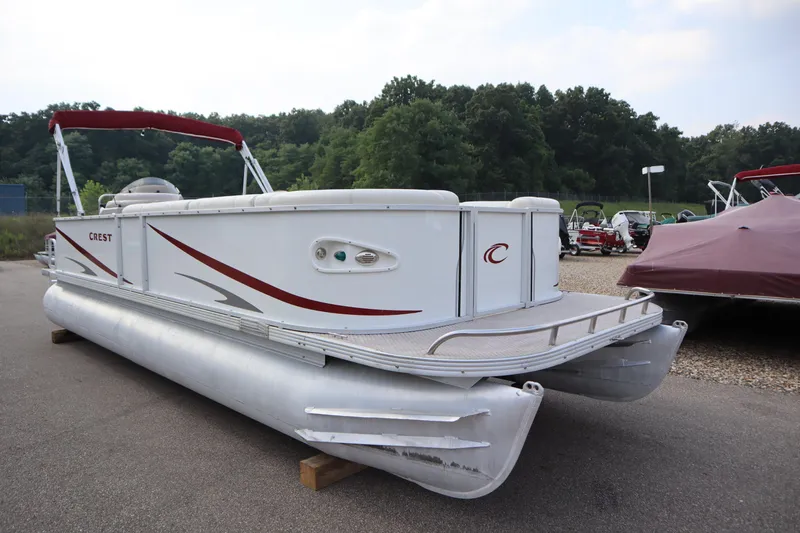 Slide: The Image of 2005 Crest 25 Caribbean pontoon boat with red accents, parked outdoors. - 3