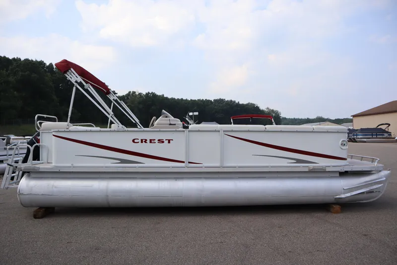 Slide: The Image of 2005 Crest 25 Caribbean pontoon boat with red accents, parked outdoors. - 4