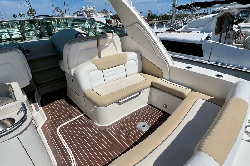 Slide: The Image of 2010 Sea Ray 350 Sundancer interior with beige seating and wood flooring at marina. - 15