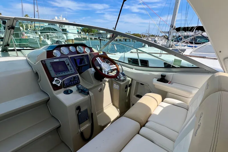 Slide: The Image of 2010 Sea Ray 350 Sundancer cockpit with steering wheel, navigation controls, and plush seating. - 25