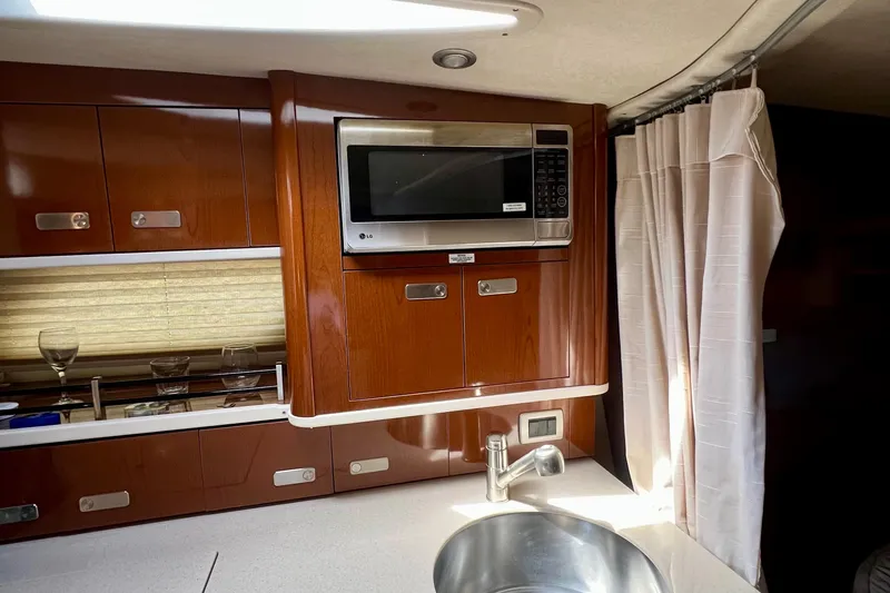 Slide: The Image of Interior of 2010 Sea Ray 350 Sundancer with microwave, sink, and wooden cabinetry. - 59
