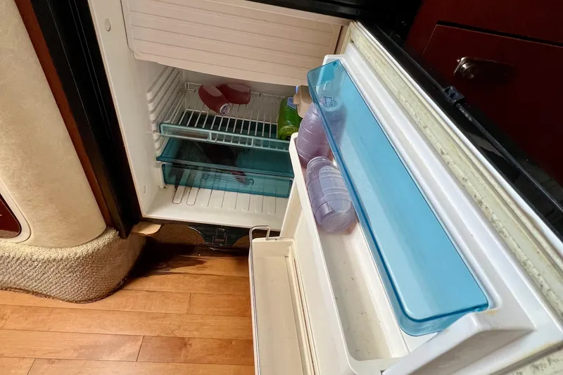 Slide: The Image of Open mini fridge inside 2010 Sea Ray 350 Sundancer boat, showing drinks and storage. - 63