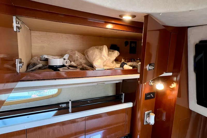 Slide: The Image of Open cabinet in 2010 Sea Ray 350 Sundancer boat interior, showing stored items. - 69