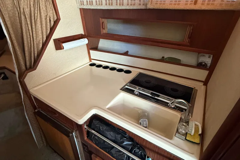 Slide: The Image of 1986 Sea Ray 300 Weekender galley with stove, sink, and storage. - 18