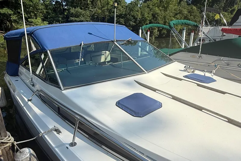 Slide: The Image of 1986 Sea Ray 300 Weekender boat with blue canopy docked near lush greenery. - 4