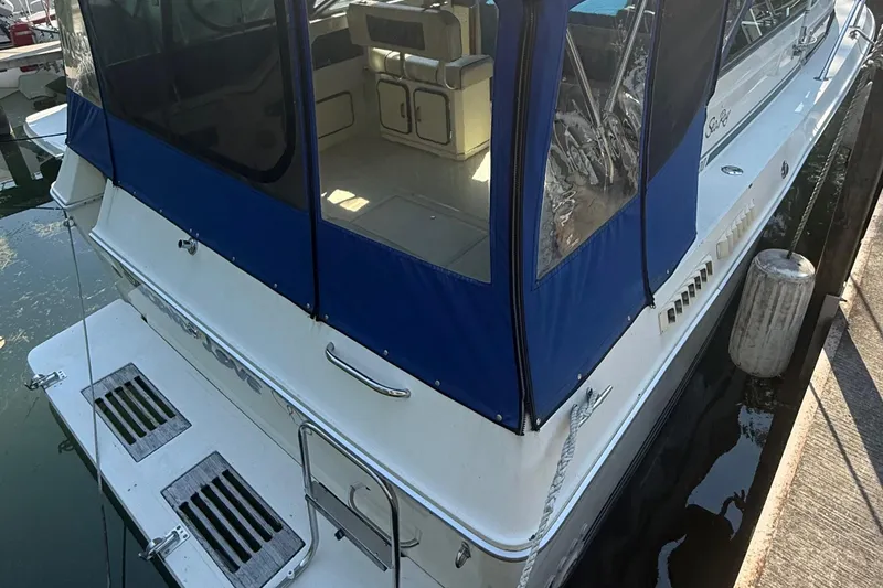 Slide: The Image of 1986 Sea Ray 300 Weekender boat docked with blue canopy and visible interior. - 6