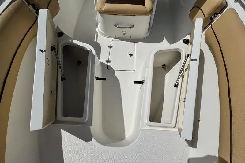Slide: The Image of 2016 NauticStar 25 XS boat interior with open storage compartments and tan seating. - 16
