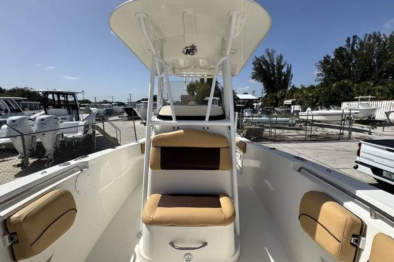 Slide: The Image of 2016 NauticStar 25 XS boat interior with tan seating and T-top in a marina setting. - 17