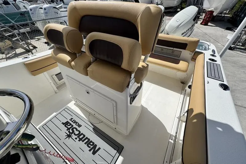 Slide: The Image of 2016 NauticStar 25 XS boat interior with tan and black seating, steering wheel, and branded mat. - 23