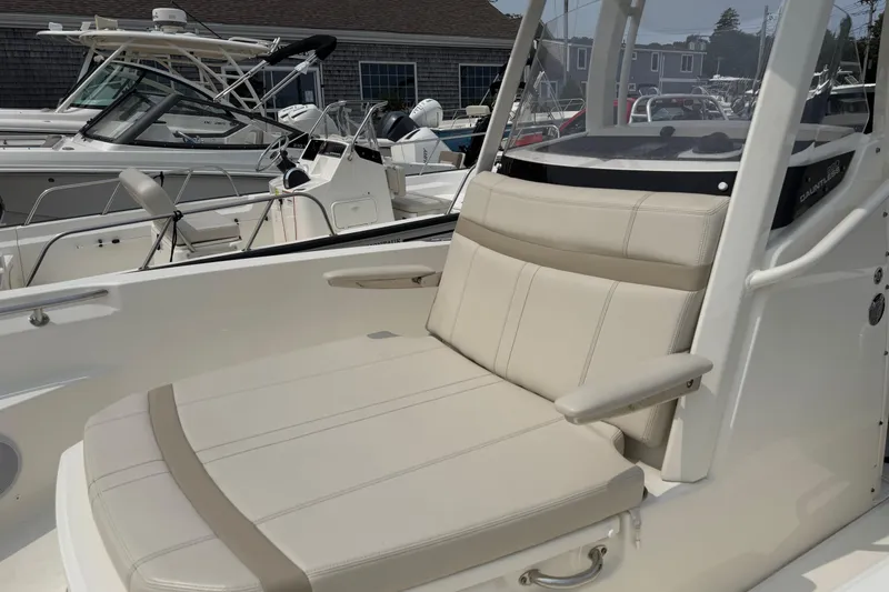 Slide: The Image of 2024 Boston Whaler 220 Dauntless boat interior with beige seating and console. - 2