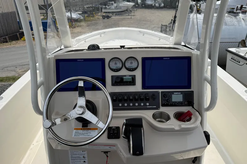 Slide: The Image of 2024 Boston Whaler 220 Dauntless boat dashboard with steering wheel and navigation screens. - 5