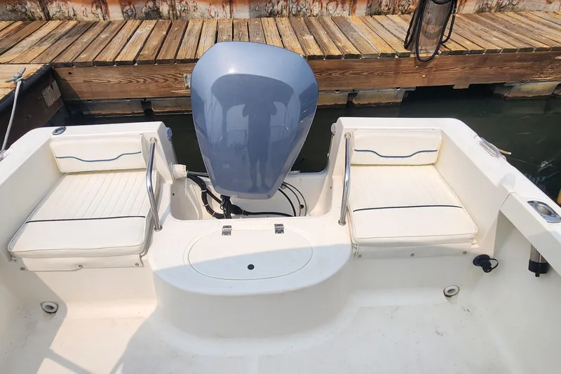 Slide: The Image of 2001 Sea Hunt 19 Dual Console boat interior with seating and motor, docked by wooden pier. - 11
