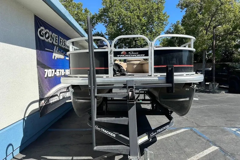 Slide: The Image of 2019 Sun Tracker Bass Buggy 18 DLX pontoon boat on trailer, parked outdoors. - 3