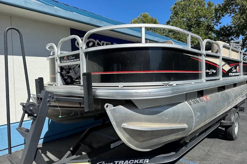 Slide: The Image of 2019 Sun Tracker Bass Buggy 18 DLX pontoon boat on trailer, parked outdoors. - 5