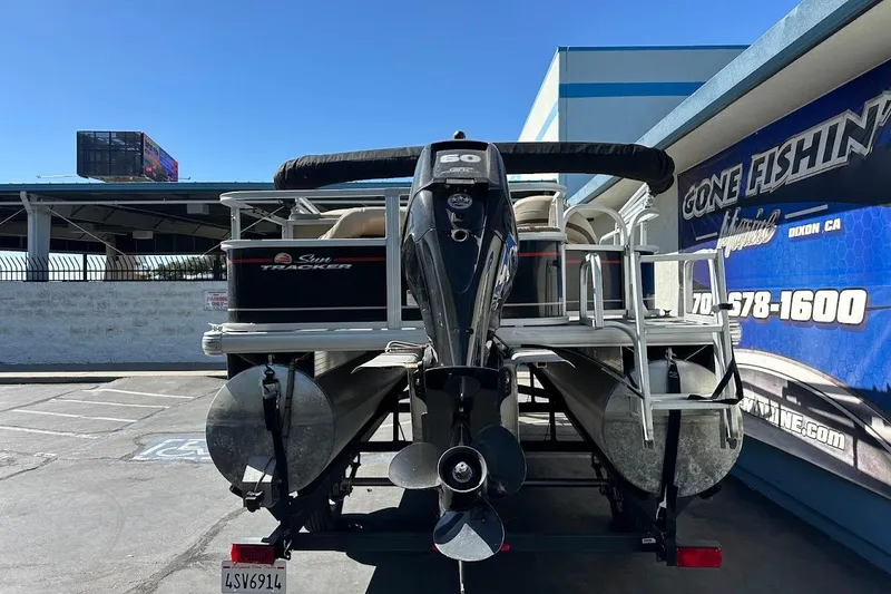 Slide: The Image of 2019 Sun Tracker Bass Buggy 18 DLX pontoon boat with outboard motor, parked at dealership. - 9