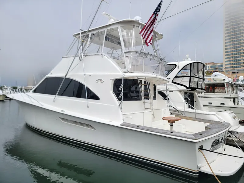 The Image of 2001 Ocean Yachts 56 Super Sport docked at marina, featuring flybridge and American flag. - 1