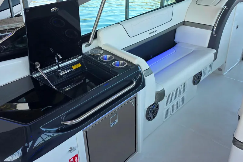 Slide: The Image of 2026 Formula 350 Crossover Bowrider I/O interior with sleek cabinetry and stainless steel fridge. - 24