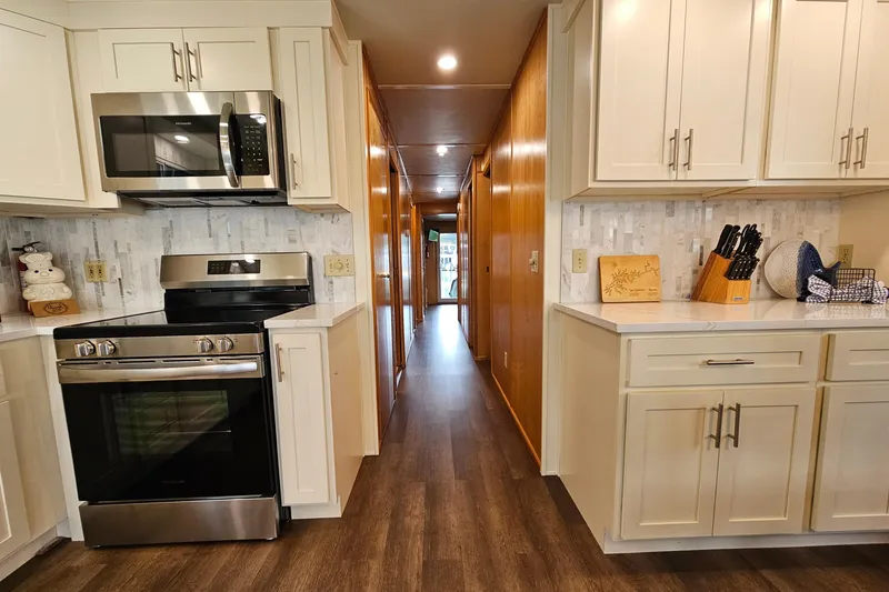 Slide: The Image of Modern kitchen with stainless steel appliances, white cabinets, and wood flooring in a Fantasy 18x80 model. - 10