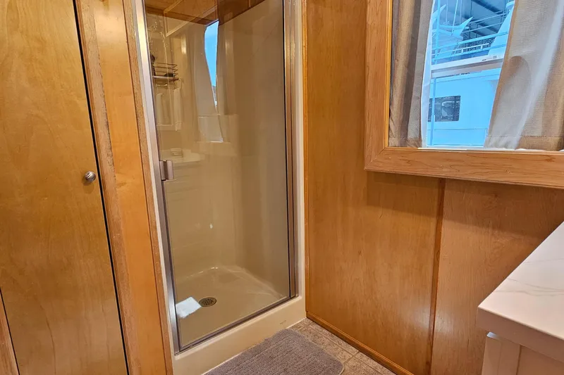 Slide: The Image of Wood-paneled bathroom with glass shower, window, and countertop in a 2001 Fantasy 18x80 model. - 18