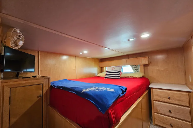 Slide: The Image of Cozy bedroom in 2001 Fantasy 18x80 houseboat with red bedding, TV, and wooden cabinetry. - 29