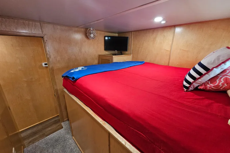 Slide: The Image of Cozy bedroom with red bedding, wood paneling, and a small TV in a Fantasy 18x80 model. - 30