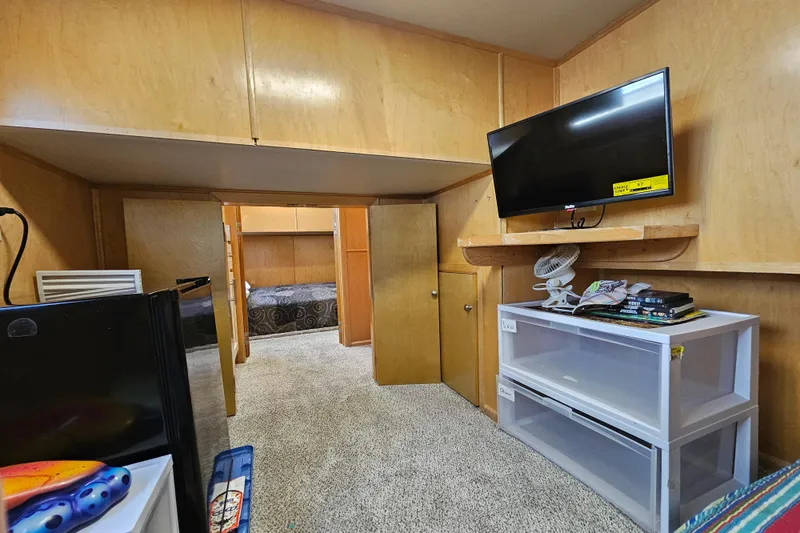 Slide: The Image of Compact room with wood paneling, TV, mini fridge, and storage, leading to a cozy bedroom. - 36