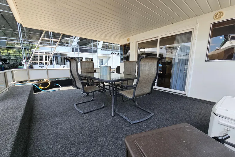 Slide: The Image of Outdoor seating area on a 2001 Fantasy 18x80 houseboat, featuring a table and chairs. - 4