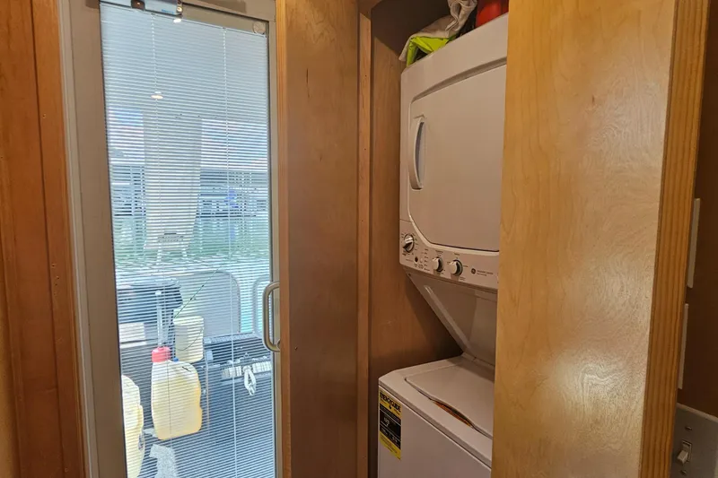 Slide: The Image of Compact laundry area with stacked washer-dryer beside a glass door on a Fantasy 18x80 houseboat. - 40