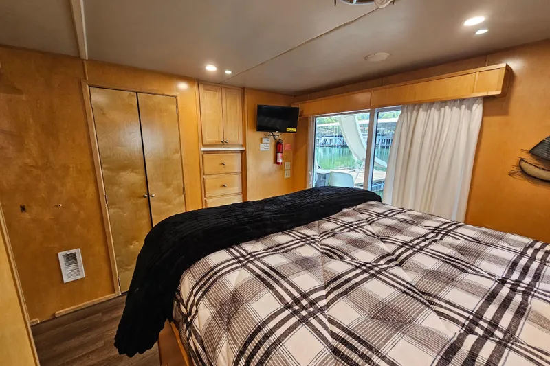 Slide: The Image of Cozy bedroom in 2001 Fantasy 18x80 houseboat with plaid bedding and wood paneling. - 45