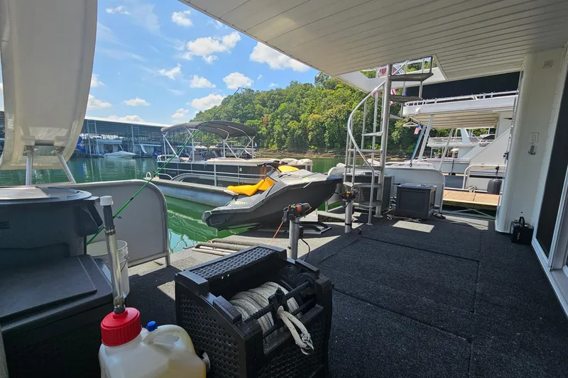 Slide: The Image of Houseboat deck with spiral staircase, jet ski, and marina view under a clear sky. - 49