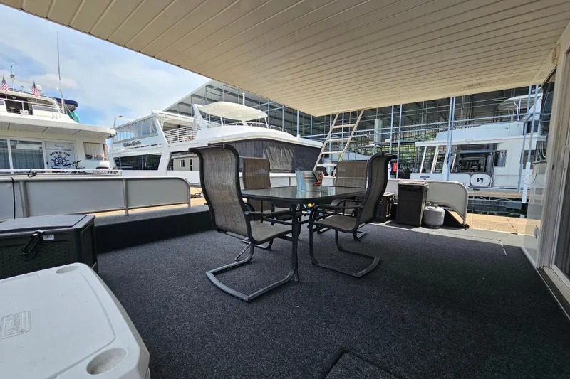 Slide: The Image of Outdoor seating area on a 2001 Fantasy 18x80 houseboat, docked with other boats nearby. - 5